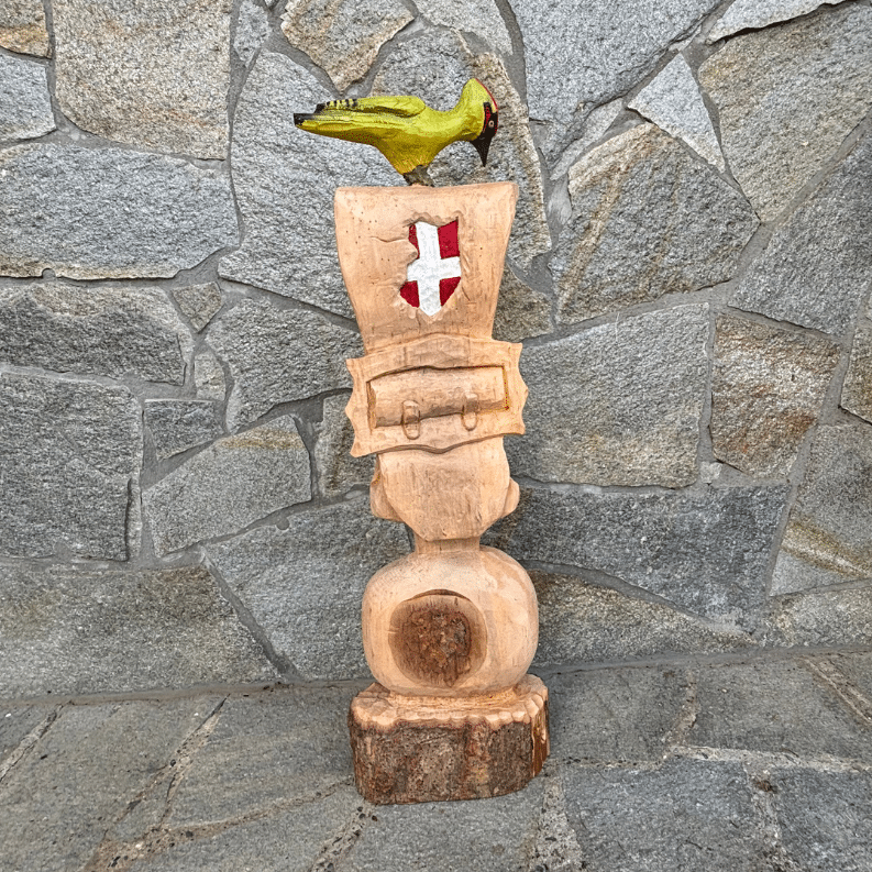 Sculpture en bois représentant une cloche de vache avec une croix de Savoie et un pivert au dessus
